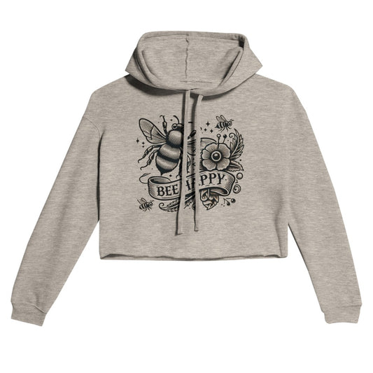 Women’s cropped hoodie adorned with a classic tattoo style design in black and white, featuring a bee, a flower, and the words ‘bee happy’ encased within a banner. Ideal for a trendy look. Available in a range of colours - this one is Heather Dust, a light shade of grey.